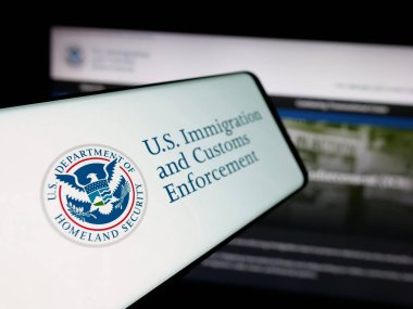 Stuttgart, Almanya - 03-18-2025: İnternet sitesi önünde üzerinde ABD Göçmenlik ve Gümrük Uygulaması (ICE) logosu bulunan akıllı telefon. Telefon ekranının merkez soluna odaklan.