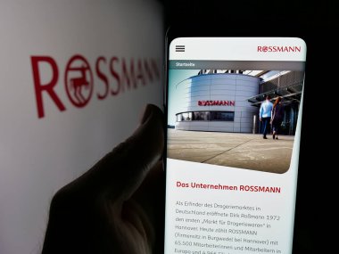 Stuttgart, Almanya - 03-19-2025: Üzerinde Alman perakende şirketi Dirk Rossmann GmbH 'nin logosu bulunan web sayfası logonun önünde duruyor. Telefon ekranının merkezine odaklan.