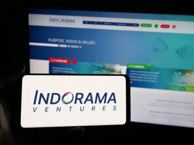 Stuttgart, Almanya - 03-19-2025: İnternet sitesinin önünde ekranda Tayland petrokimya şirketi Indorama Ventures 'in logosuna sahip akıllı telefon tutan kişi. Telefon ekranına odaklan.