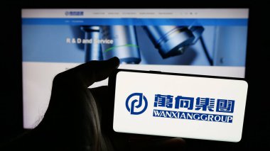 Stuttgart, Almanya - 03-19-2025: Çinli Wanxiang Group Corporation şirketinin logosunun bulunduğu cep telefonu web sayfası önünde ekranda. Telefon ekranına odaklan.