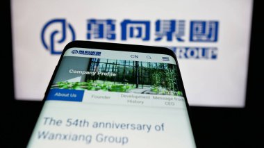 Stuttgart, Almanya - 03-19-2025: Çin şirketi Wanxiang Group Corporation 'ın logosunu içeren cep telefonu web sitesinin önünde ekranda. Telefon ekranının sol üst kısmına odaklan.