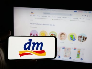 Stuttgart, Almanya - 03-19-2025: Alman şirketi dm-drogerie markt GmbH Co. KG 'nin logosunu taşıyan kişi web sitesinin önünde ekranda. Telefon ekranına odaklan.