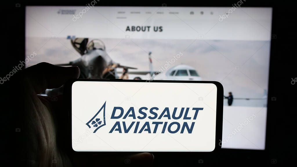 Stuttgart, Germany - 03-13-2025: Person holding cellphone with logo of French company Dassault Aviation S.A. on screen in front of webpage. Focus on phone display.