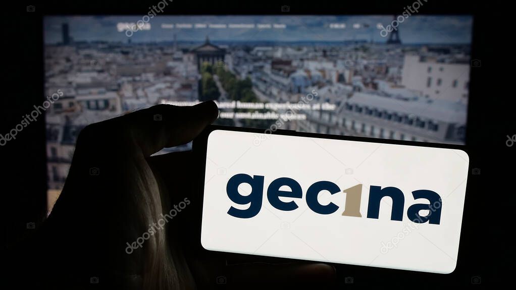 Stuttgart, Germany - 03-14-2025: Person holding mobile phone with logo of French real estate company Gecina S.A. on screen in front of web page. Focus on phone display.