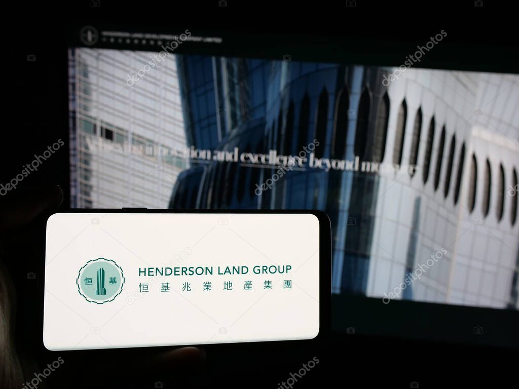 Stuttgart, Germany - 03-14-2025: Person holding smartphone with logo of company Henderson Land Development Co. Ltd. on screen in front of website. Focus on phone display.