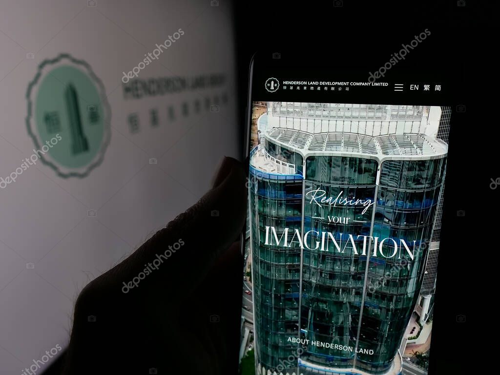 Stuttgart, Germany - 03-14-2025: Person holding cellphone with webpage of company Henderson Land Development Co. Ltd. on screen in front of logo. Focus on center of phone display.