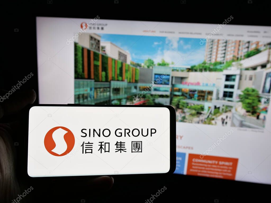 Stuttgart, Germany - 03-14-2025: Person holding smartphone with logo of Hong Kong real estate company Sino Group on screen in front of website. Focus on phone display.
