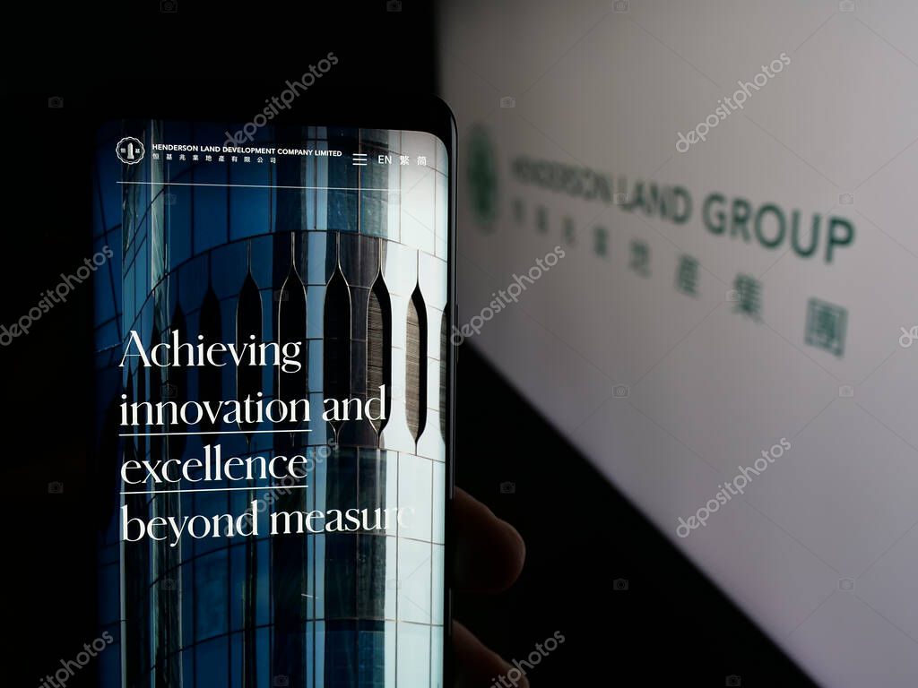 Stuttgart, Germany - 03-14-2025: Person holding web page with logo of company Henderson Land Development Co. Ltd. on screen in front of logo. Focus on center of phone display.