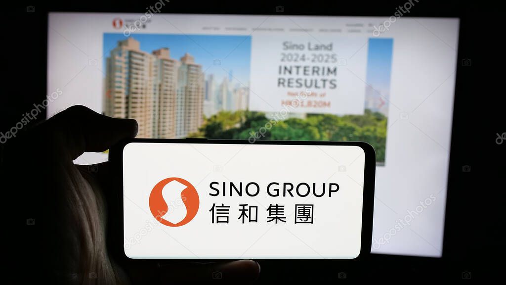 Stuttgart, Germany - 03-14-2025: Person holding cellphone with logo of Hong Kong real estate company Sino Group on screen in front of webpage. Focus on phone display.