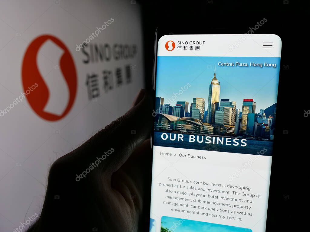 Stuttgart, Germany - 03-14-2025: Person holding cellphone with webpage of Hong Kong real estate company Sino Group on screen in front of logo. Focus on center of phone display.