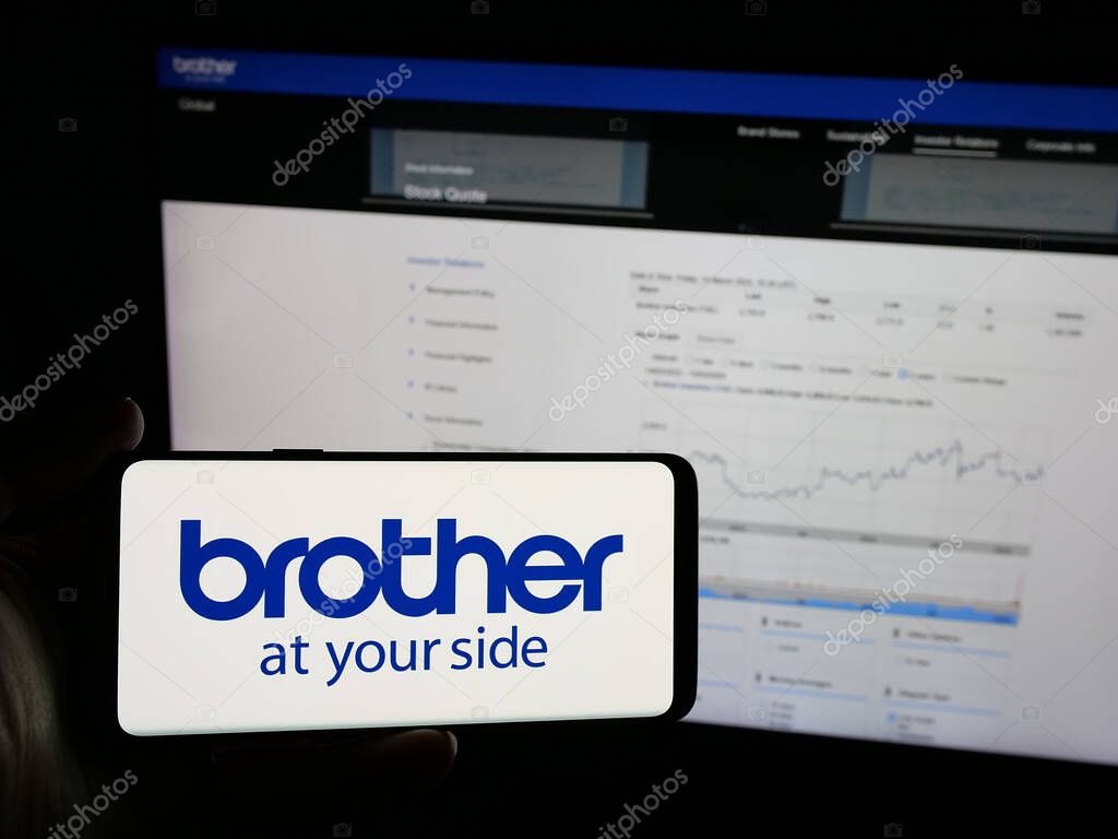 Stuttgart, Germany - 03-14-2025: Person holding smartphone with logo of electronics company Brother Industries Ltd. on screen in front of website. Focus on phone display.