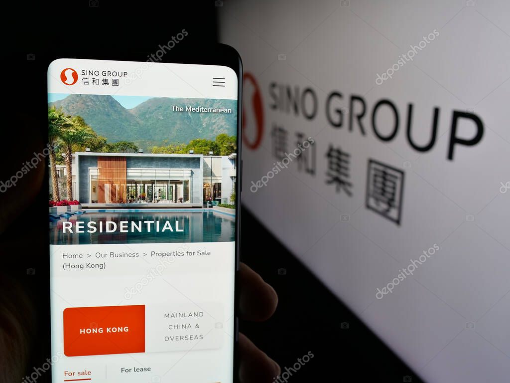 Stuttgart, Germany - 03-14-2025: Person holding web page with logo of Hong Kong real estate company Sino Group on screen in front of logo. Focus on center of phone display.