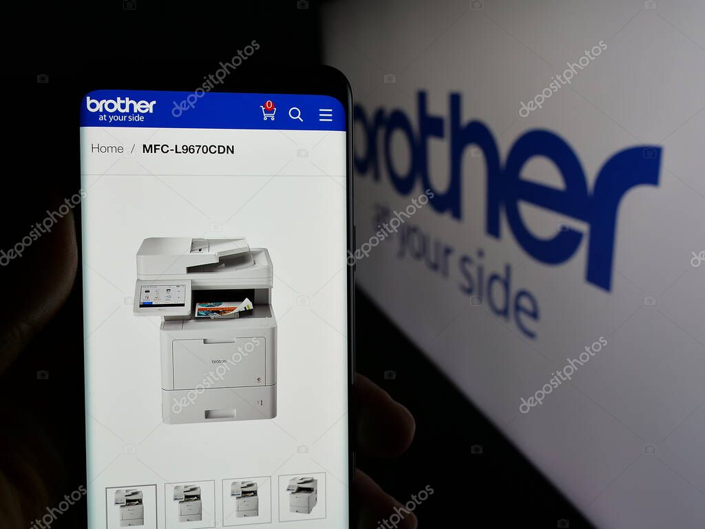 Stuttgart, Germany - 03-14-2025: Person holding cellphone with webpage of electronics company Brother Industries Ltd. on screen in front of logo. Focus on center of phone display.