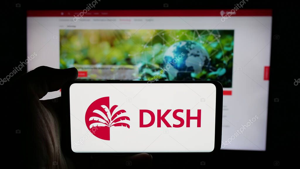 Stuttgart, Germany - 03-19-2025: Person holding cellphone with logo of Swiss outsourcing company DKSH Holding AG on screen in front of webpage. Focus on phone display.