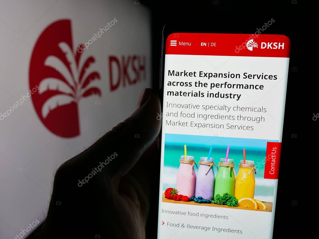 Stuttgart, Germany - 03-19-2025: Person holding web page with logo of Swiss outsourcing company DKSH Holding AG on screen in front of logo. Focus on center of phone display.