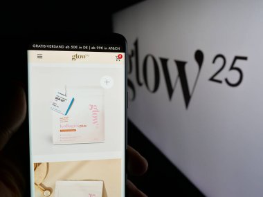 Stuttgart, Almanya - 03-20-2025: Alman kolajen şirketi Glow25 'in (Primal) web sayfası logonun önünde cep telefonu tutan kişi. Telefon ekranının merkezine odaklan.