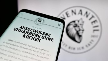 Stuttgart, Almanya - 03-20-2025: Alman organik gıda şirketi Lowenanteil GmbH 'nin logosunu içeren cep telefonu web sitesinin önünde ekranda. Telefon ekranının sol üst kısmına odaklan.