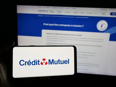 Stuttgart, Almanya - 03-21-2025: Fransız bankası Caisse Federale de Credit Mutuel 'in logosunu taşıyan kişi web sitesinin önünde ekranda. Telefon ekranına odaklan.