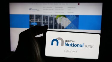 Stuttgart, Almanya - 03-21-2025: İnternet sayfasının önünde üzerinde Belçika Ulusal Bankası 'nın (NBB) logosu bulunan cep telefonu sahibi kişi. Telefon ekranına odaklan.