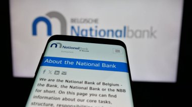 Stuttgart, Almanya - 03-21-2025: İnternet sitesinin önünde üzerinde Belçika Ulusal Bankası van Belgie (NBB) logosu bulunan cep telefonu. Telefon ekranının sol üst kısmına odaklan.