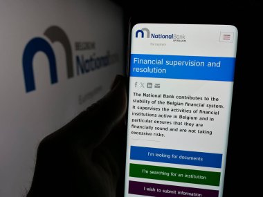 Stuttgart, Almanya - 03-21-2025: Logonun önünde Belçika Ulusal Bankası 'nın (NBB) logosunun logosu bulunan kişi. Telefon ekranının merkezine odaklan.