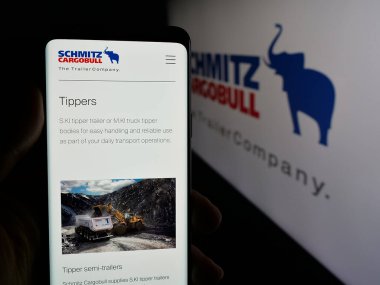 Stuttgart, Almanya - 03-24-2025: Alman karavan şirketi Schmitz Cargobull AG 'nin web sayfası ile logo önünde cep telefonu tutan kişi. Telefon ekranının merkezine odaklan.