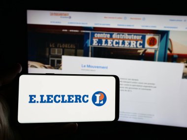 Stuttgart, Almanya - 03-24-2025: Fransız perakende şirketi E.Leclerc 'in logosuna sahip akıllı telefon sahibi kişi web sitesinin önünde ekranda. Telefon ekranına odaklan.