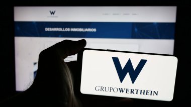 Stuttgart, Almanya - 03-24-2025: Arjantinli şirket Grupo Werthein 'in logosunun bulunduğu cep telefonu web sayfası önünde ekranda. Telefon ekranına odaklan.