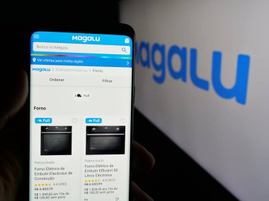 Stuttgart, Almanya - 03-24-2025: Logo önünde perakende şirketi Luiza S.A. 'nın (Magalu) web sayfası bulunan cep telefonu sahibi. Telefon ekranının merkezine odaklan.