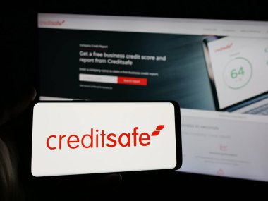 Stuttgart, Almanya - 03-24-2025: İrlandalı kredi notu şirketi Creditsafe Group 'un logosunu elinde tutan kişi web sitesinin önünde ekranda. Telefon ekranına odaklan.