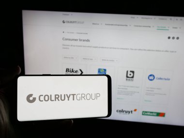 Stuttgart, Almanya - 03-24-2025: Belçikalı perakende şirketi Colruyt Group NV 'nin logosunun bulunduğu akıllı telefonu web sitesi önünde elinde tutan kişi. Telefon ekranına odaklan.