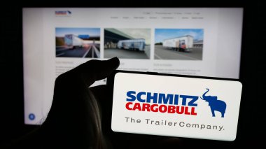 Stuttgart, Almanya - 03-24-2025: Alman karavan şirketi Schmitz Cargobull AG 'nin logosunu taşıyan cep telefonu sahibi kişi web sayfasının önünde ekranda. Telefon ekranına odaklan.