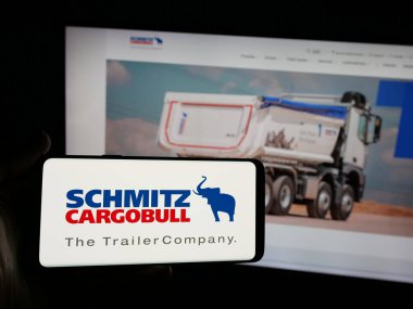 Stuttgart, Almanya - 03-24-2025: Alman karavan şirketi Schmitz Cargobull AG 'nin logosunu elinde tutan kişi web sitesinin önünde ekranda. Telefon ekranına odaklan.