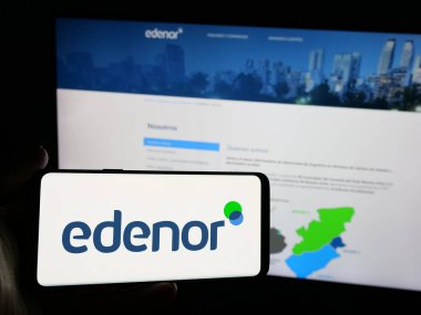 Stuttgart, Almanya - 03-27-2025: Arjantinli enerji şirketi Edenor S.A. 'nın logosunu elinde tutan kişi web sitesinin önünde ekranda. Telefon ekranına odaklan.