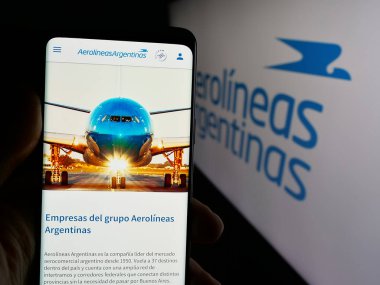 Stuttgart, Almanya - 03-27-2025: Havayolu şirketi Aerolineas Argentinas S.A. 'nın web sayfası ile cep telefonu tutan kişi logonun önünde ekranda. Telefon ekranının merkezine odaklan.