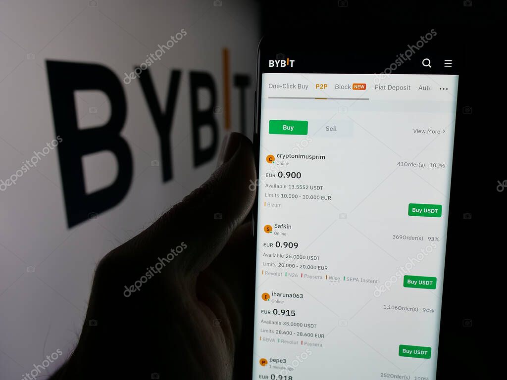 Stuttgart, Germany - 03-20-2025: Person holding web page with logo of crypto exchange company Bybit Fintech Limited on screen in front of logo. Focus on center of phone display.