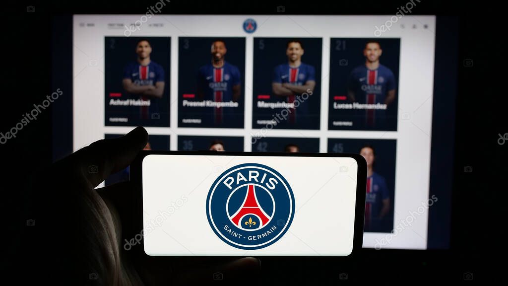 Stuttgart, Germany - 03-21-2025: Person holding cellphone with logo of Paris Saint-Germain Football Club (PSG) on screen in front of webpage. Focus on phone display.