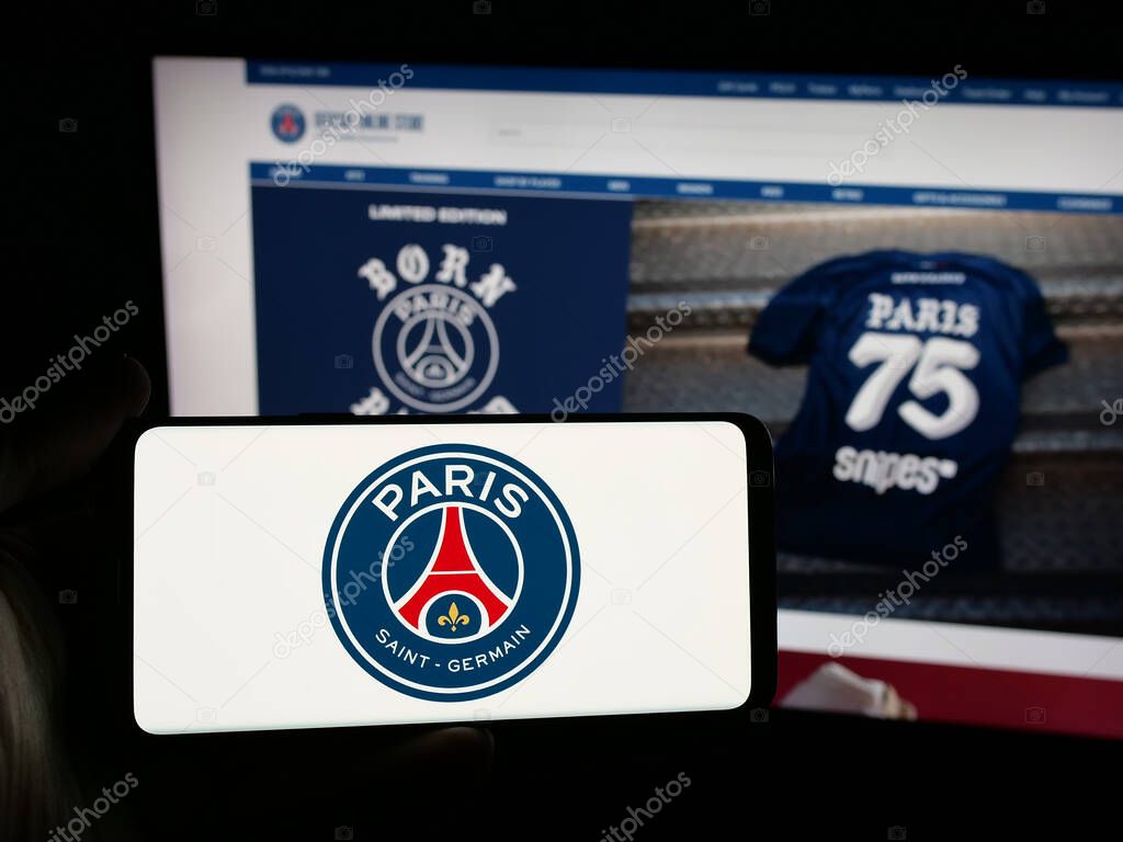 Stuttgart, Germany - 03-21-2025: Person holding smartphone with logo of Paris Saint-Germain Football Club (PSG) on screen in front of website. Focus on phone display.