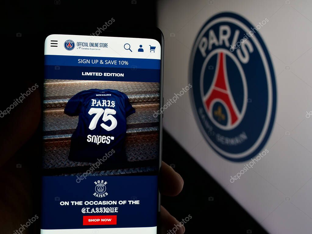 Stuttgart, Germany - 03-21-2025: Person holding cellphone with webpage of Paris Saint-Germain Football Club (PSG) on screen in front of logo. Focus on center of phone display.
