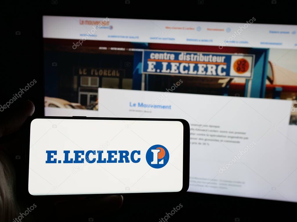 Stuttgart, Germany - 03-24-2025: Person holding smartphone with logo of French retail company E.Leclerc on screen in front of website. Focus on phone display.