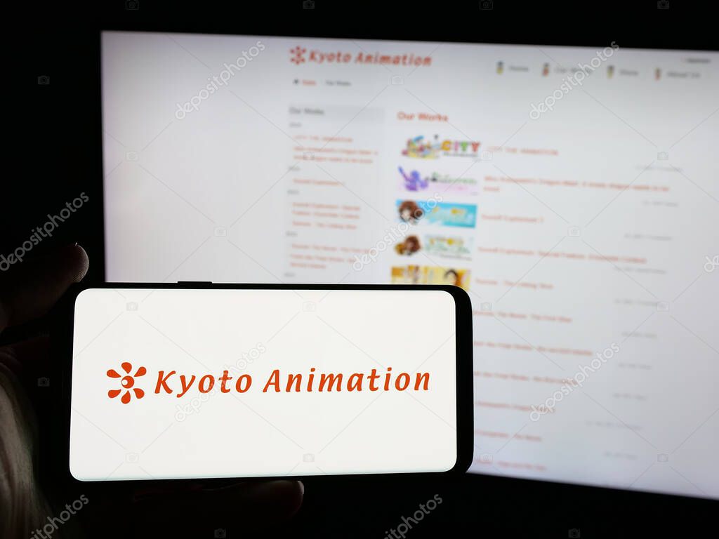 Stuttgart, Germany - 03-24-2025: Person holding smartphone with logo of Japanese company Kyoto Animation Co. Ltd. on screen in front of website. Focus on phone display.