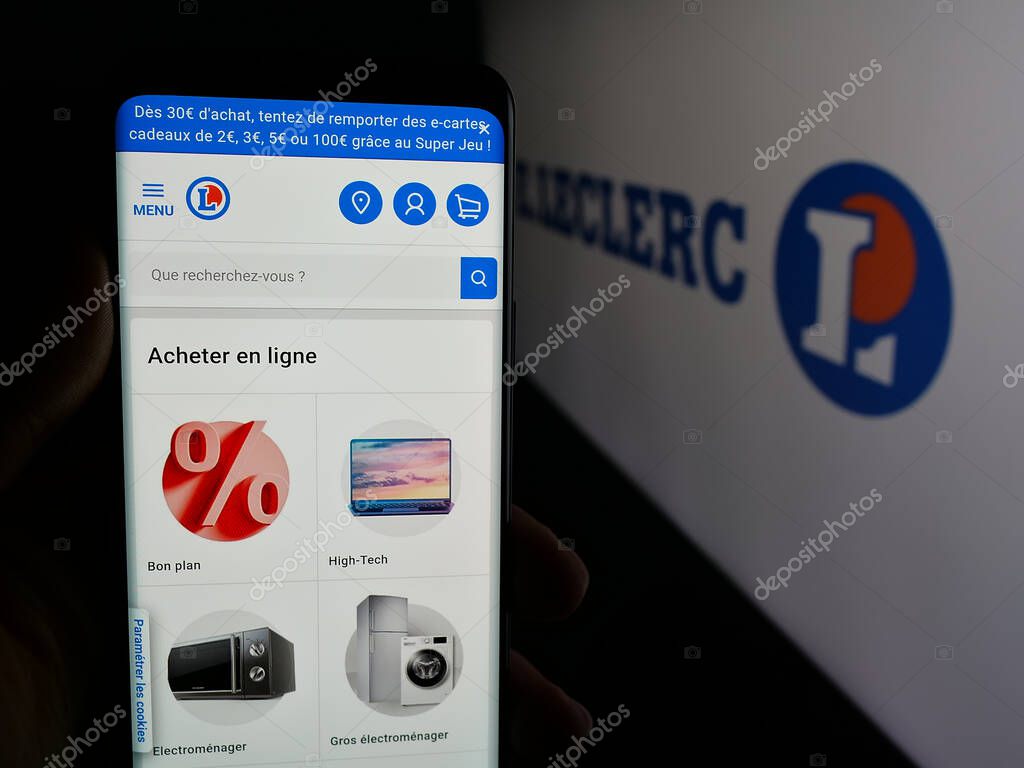 Stuttgart, Germany - 03-24-2025: Person holding cellphone with webpage of French retail company E.Leclerc on screen in front of logo. Focus on center of phone display.
