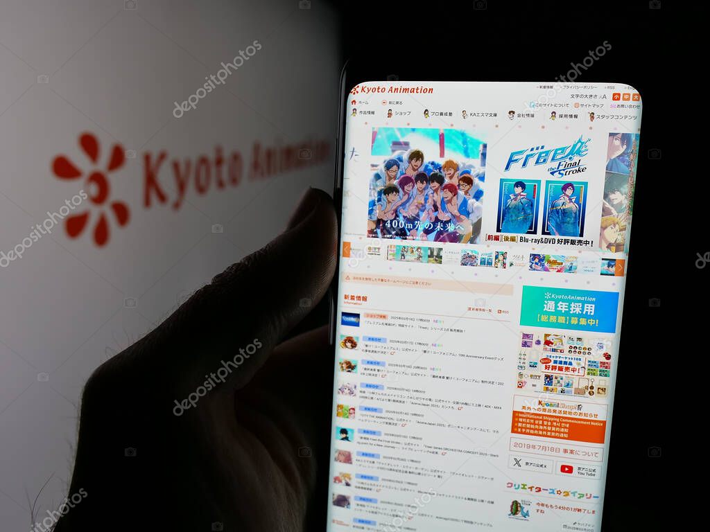 Stuttgart, Germany - 03-24-2025: Person holding web page with logo of Japanese company Kyoto Animation Co. Ltd. on screen in front of logo. Focus on center of phone display.