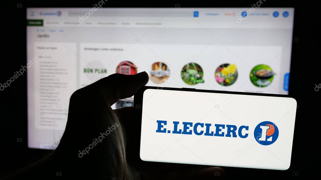 Stuttgart, Germany - 03-24-2025: Person holding mobile phone with logo of French retail company E.Leclerc on screen in front of web page. Focus on phone display.