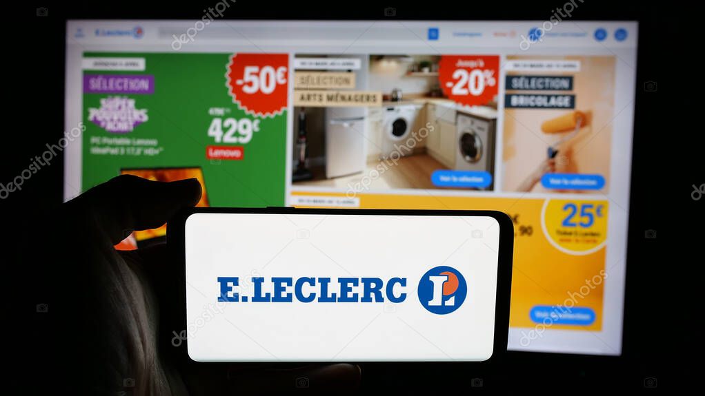 Stuttgart, Germany - 03-24-2025: Person holding cellphone with logo of French retail company E.Leclerc on screen in front of webpage. Focus on phone display.