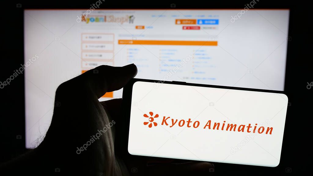 Stuttgart, Germany - 03-24-2025: Person holding mobile phone with logo of Japanese company Kyoto Animation Co. Ltd. on screen in front of web page. Focus on phone display.