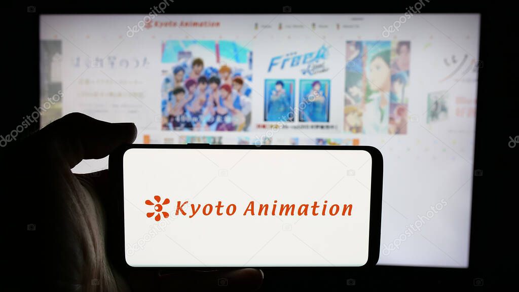 Stuttgart, Germany - 03-24-2025: Person holding cellphone with logo of Japanese company Kyoto Animation Co. Ltd. on screen in front of webpage. Focus on phone display.