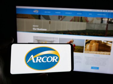 Stuttgart, Almanya - 03-27-2025: Şekerleme şirketi Arcor S.A.I.C. 'nin logosuna sahip akıllı telefon sahibi kişi Web sitesinin önünde ekranda. Telefon ekranına odaklan.
