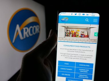 Stuttgart, Almanya - 03-27-2025: Arcor S.A.I.C adlı şekerleme şirketinin web sayfası ile cep telefonu tutan kişi Ekranda logonun önünde. Telefon ekranının merkezine odaklan.