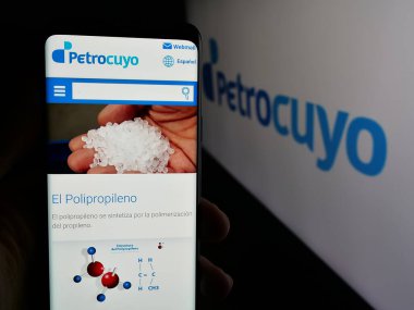 Stuttgart, Almanya - 03-31-2025: Logo önünde Petroquimica Cuyo SAIC (Petrocuyo) şirketinin web sayfası bulunan kişi. Telefon ekranının merkezine odaklan.